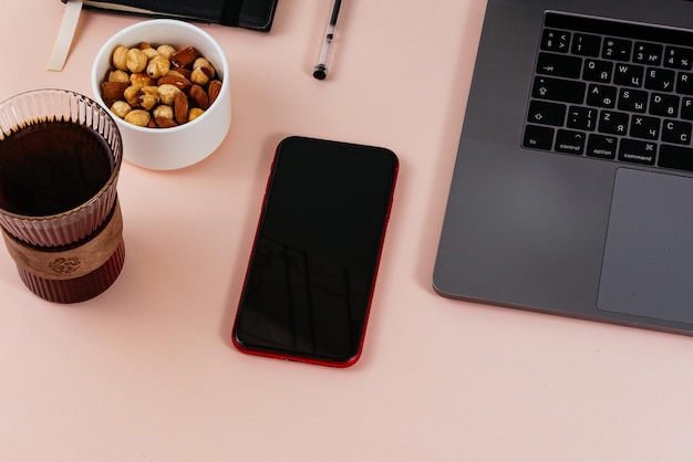 Il caffè è sul tavolo accanto al telefono e al mockup del laptop