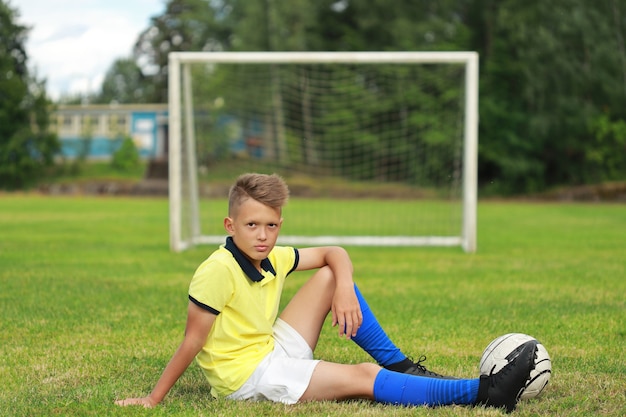 Il calciatore bello del ragazzo si trova sul campo di calcio con la palla