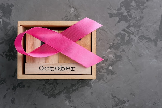 Il calendario rosa del cubo di legno e del nastro ha fissato per il 15 ottobre su una superficie di calcestruzzo, il mese di consapevolezza del cancro al seno