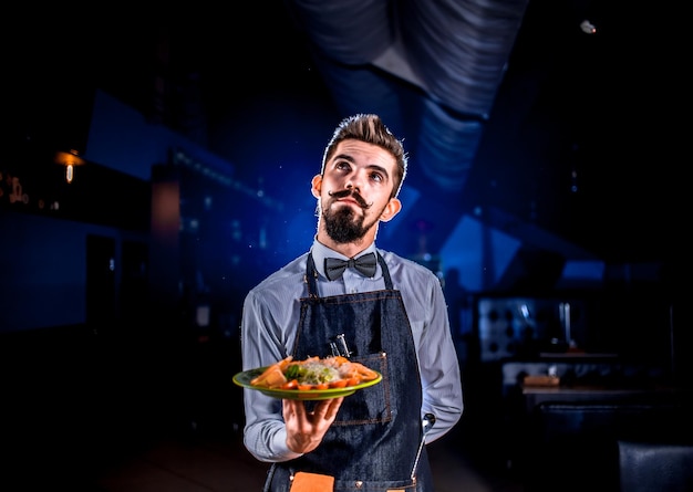 Il cameriere professionista tiene il piatto con il piatto preparato nel ristorante.