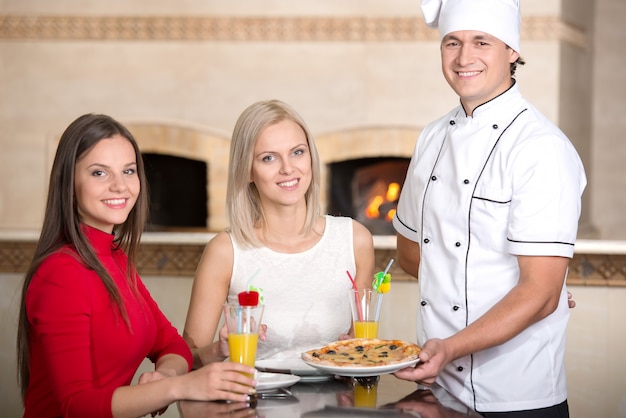 Il cameriere sta servendo la pizza alla giovane donna in un ristorante.