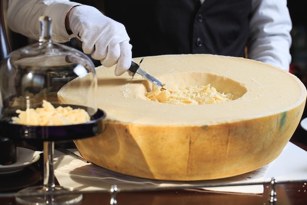 Il cameriere taglia dei pezzi di parmigiano