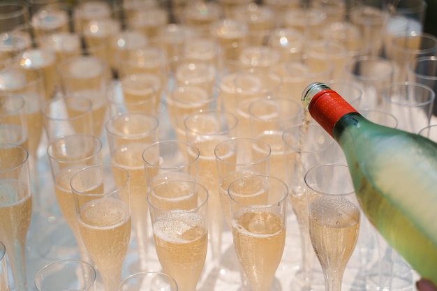 Il cameriere versa lo champagne in una tazza di vino in plastica usa e getta