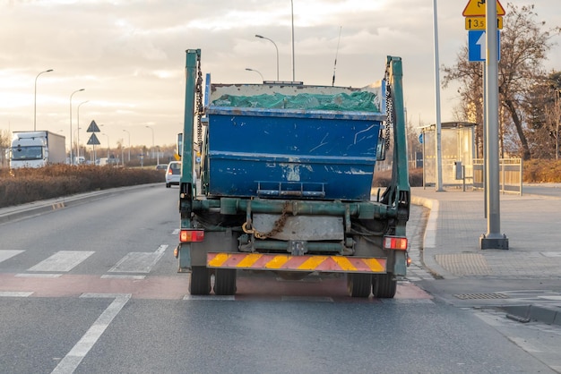 Il camion della spazzatura attraversa la città tirando fuori un contenitore con rifiuti ingombranti