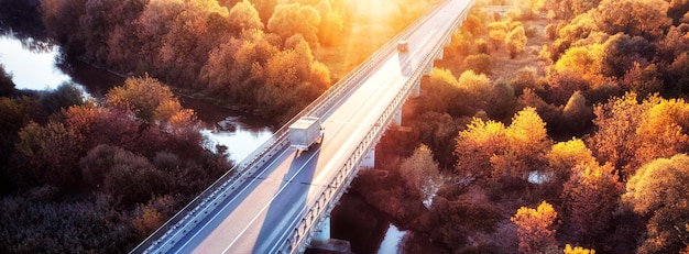 Il camion sta attraversando il ponte sul fiume Vista drone della foresta autunnale