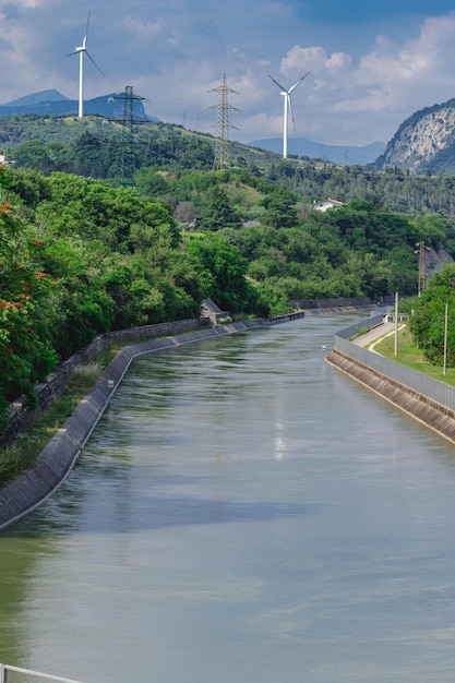 Il canale Biffis un canale artificiale per irrigazione e idroelettrica con turbine eoliche sullo sfondo insieme forniscono energia pulita alla provincia di Verona