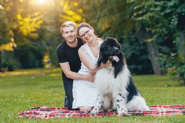 Il cane di Terranova gioca con l'uomo e la donna nel parco