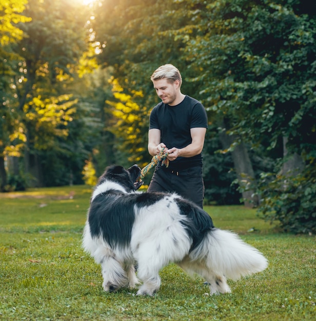 Il cane di Terranova gioca con l'uomo e la donna nel parco