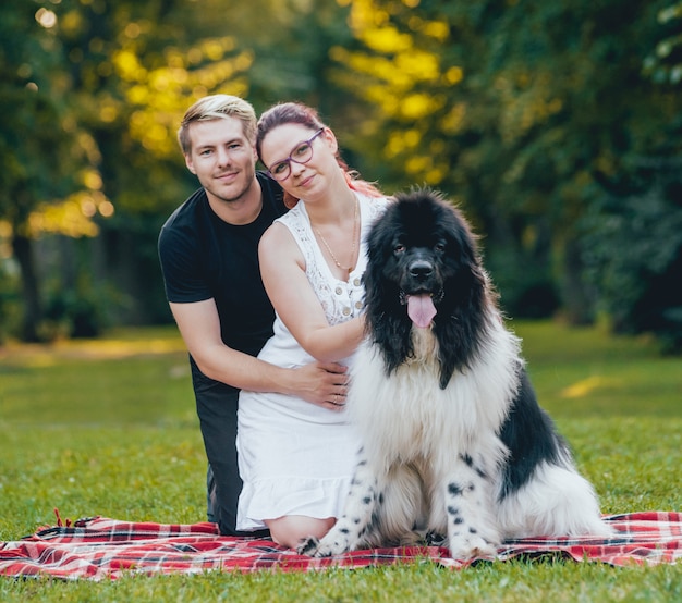 Il cane di Terranova gioca con l'uomo e la donna nel parco