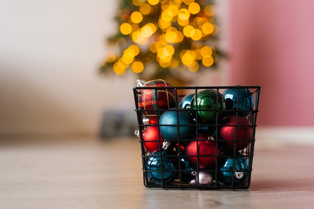 Il canestro del metallo con le palle di Natale gioca sul delle luci di Natale sull'albero