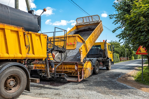 Il cantiere sta posando una nuova pavimentazione stradale asfaltatalavoratori edili stradali e scena di macchine per la costruzione di strade