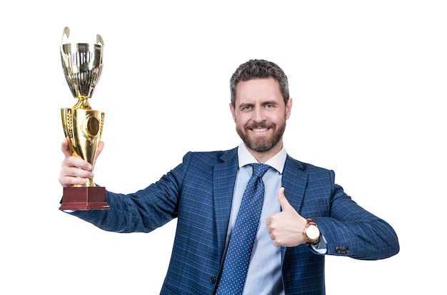 Il capo felice tiene la tazza d'oro che dà i pollici in su gesto della mano isolato su bianco migliore