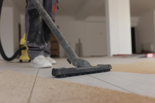Il caposquadra esegue la pulizia industriale del pavimento in laminato nella stanza durante il processo di ristrutturazione degli aspirapolvere