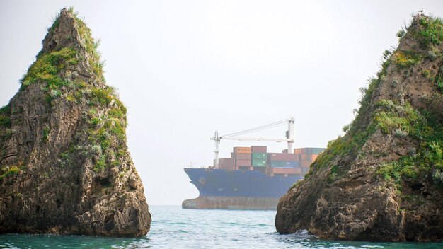 Il cargo con più container galleggia nel mare tra i due scogli