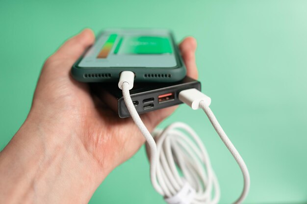 Il caricabatterie portatile carica uno smartphone isolato su uno sfondo verde Power bank