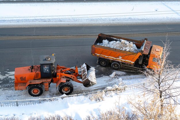 Il caricatore a fossa aperta carica la neve in un camion dopo una forte tempesta di neve