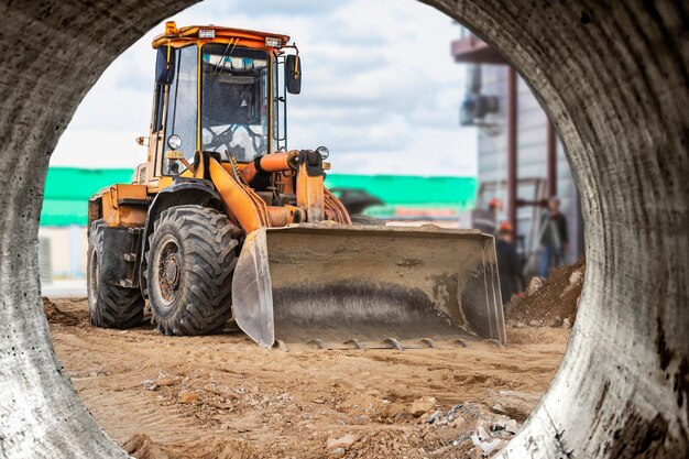 Il caricatore dell'escavatore funziona con una benna per il trasporto di sabbia in un cantiere Attrezzatura da costruzione professionale per lavori di sterro