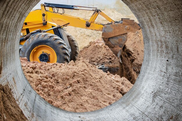 Il caricatore dell'escavatore funziona con una benna per il trasporto di sabbia in un cantiere Attrezzatura da costruzione professionale per lavori di sterro