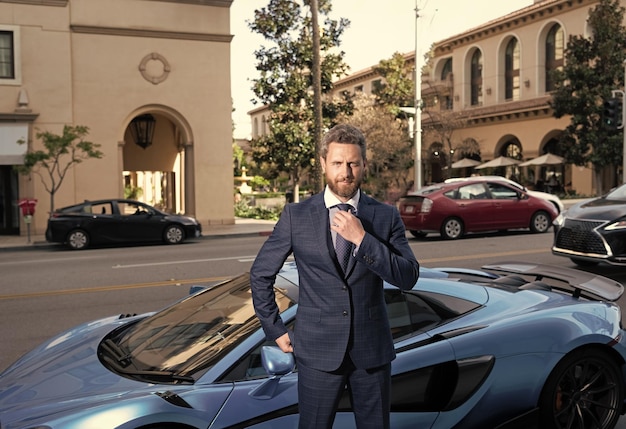 Il carismatico capo con la barba lunga si trova accanto alla vita di lusso all'aperto di colore blu dell'automobile di lusso