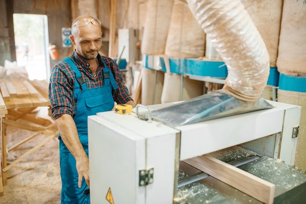 Il carpentiere lavora su macchina piana, lavorazione del legno, industria del legname, falegnameria. Lavorazione del legno su fabbrica di mobili