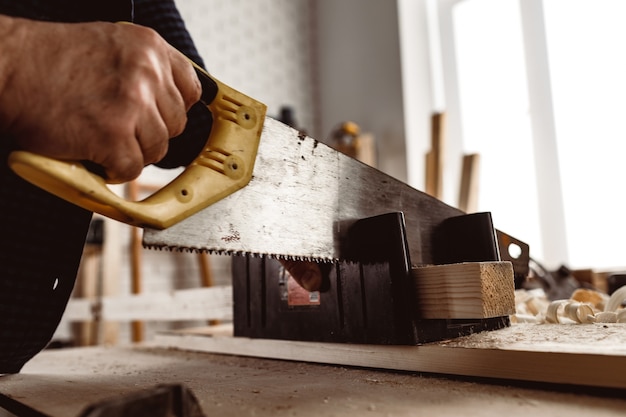 Il carpentiere sega un blocco di legno in un'officina