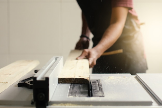 Il carpentiere taglia un pezzo di legno in officina usando una sega circolare