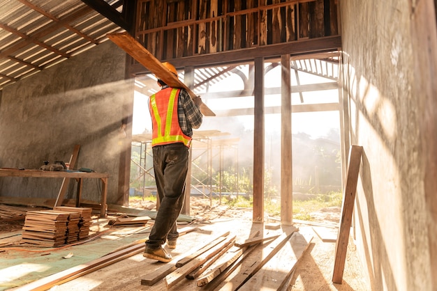 Il carpentiere tiene le assi di legno sul cantiere