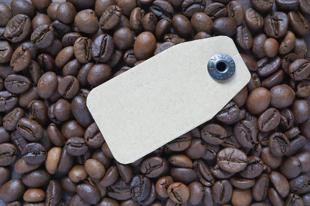 Il cartellino del prezzo del cartone giaceva su chicchi di caffè tostati marroni. etichetta per diversi tipi di caffè