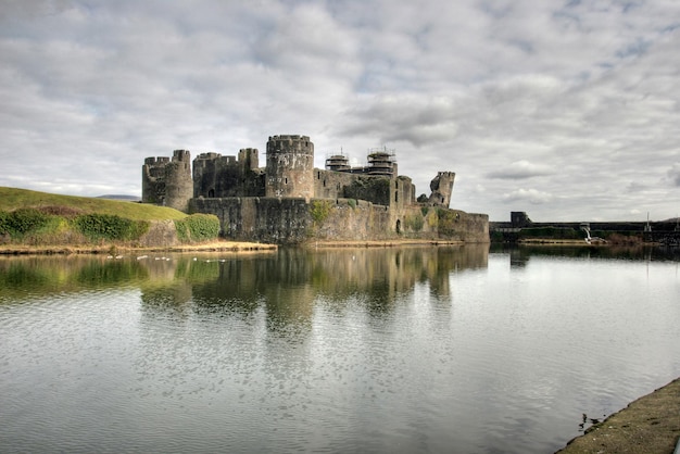 Il castello di Caerphilly vicino al lago contro un cielo nuvoloso