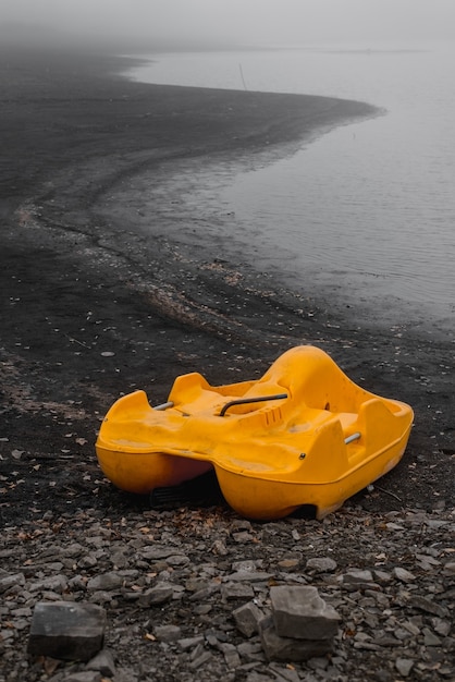 Il catamarano giallo dimenticato si trova da solo sulla costa in autunno