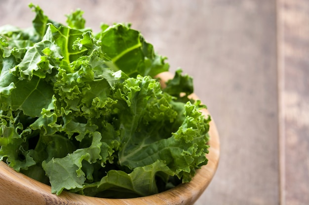 Il cavolo verde fresco del superfood in ciotola di legno va su di legno