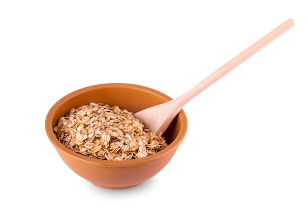 Il cereale in un cucchiaio di legno e una tazza su sfondo bianco