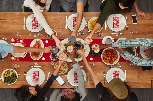 Il cibo si gusta al meglio con gli amici Inquadratura ritagliata di un gruppo di persone che brindano a un tavolo da pranzo