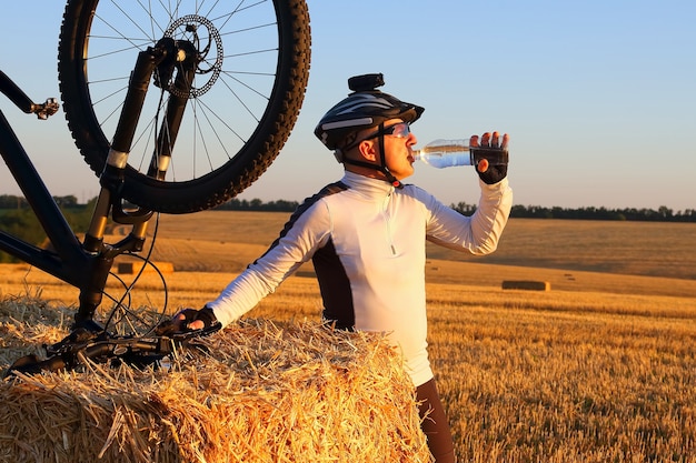 Il ciclista beve l'acqua dalla bottiglia alla luce del sole