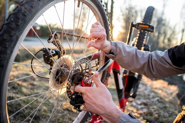 Il ciclista controlla la ruota di una bicicletta dopo aver guidato nel parco sotto i raggi del sole