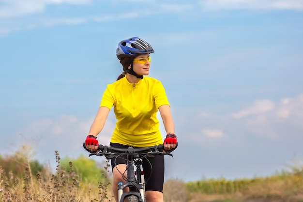 Il ciclista della bella donna guida sul campo su una bicicletta Stile di vita sano e sport