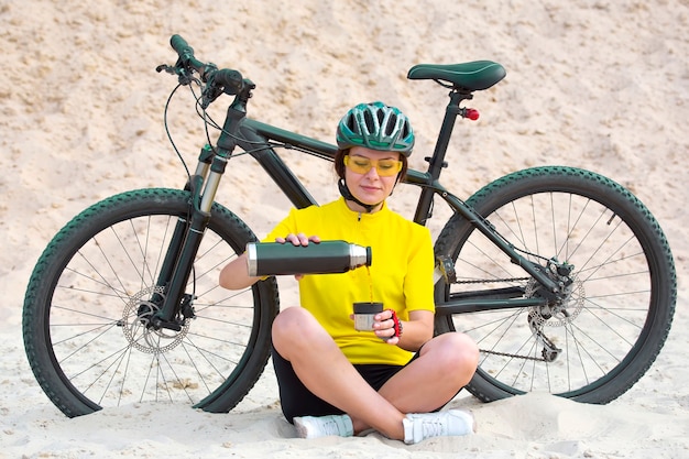 Il ciclista della bella donna versa il tè da un thermos