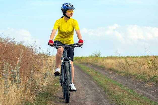 Il ciclista della donna bella e felice va in bicicletta sulla strada nella natura. Stile di vita sano e sport. Tempo libero e hobby