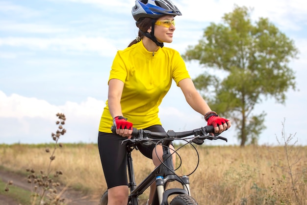 Il ciclista della donna bella e felice va in bicicletta sulla strada nella natura