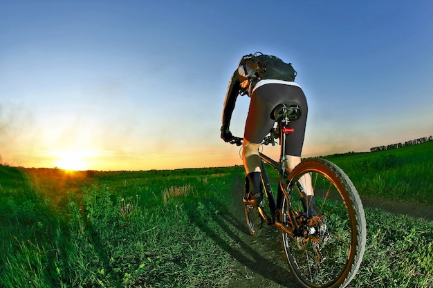 Il ciclista guida sulla strada verso il tramonto