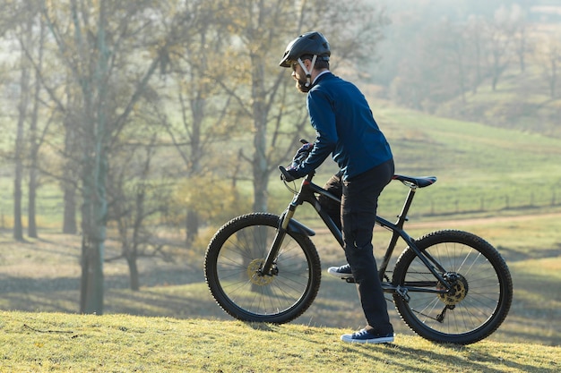 Il ciclista in pantaloni e giacca in pile su una moderna bici hardtail con forcella ammortizzata guida fuoristrada