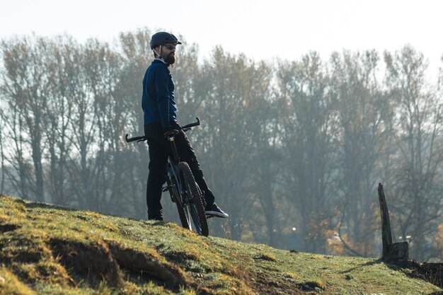 Il ciclista in pantaloni e giacca in pile su una moderna bici hardtail in carbonio con forcella a sospensione pneumatica guida fuoristrada.