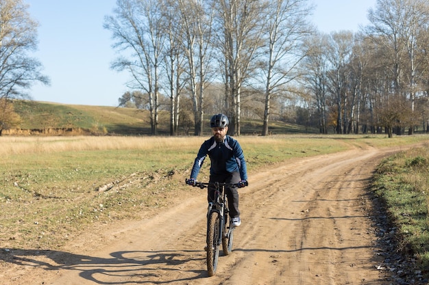 Il ciclista in pantaloni e giacca in pile su una moderna bici hardtail in carbonio con forcella a sospensione pneumatica percorre fuoristrada