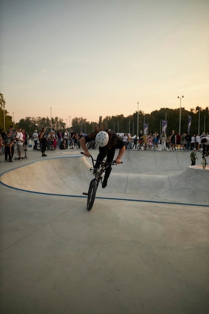 Il ciclista motociclista estremo esegue acrobazie in uno skate park Acrobazie BMX per sport estremi Skatepark affollato