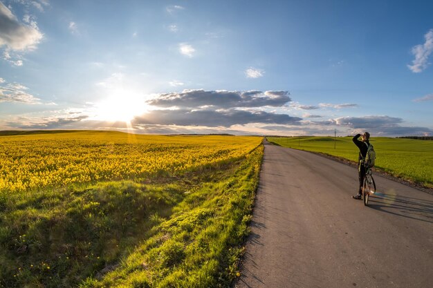 Il ciclista si trova sulla strada e guarda in lontananza e ammira il bellissimo paesaggio al tramonto