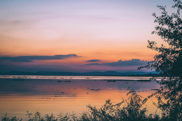 Il cielo colorato color vaniglia pastello e il riflesso del lago con le montagne sullo sfondo sfocato wil