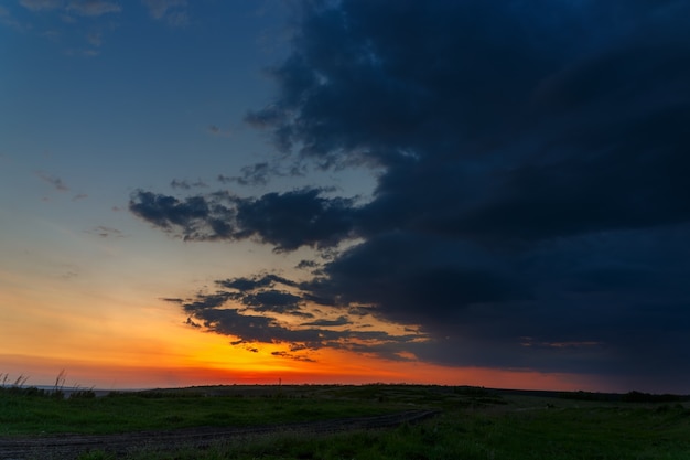 Il cielo con nuvole luminose illuminate dal sole dopo il tramonto sul campo