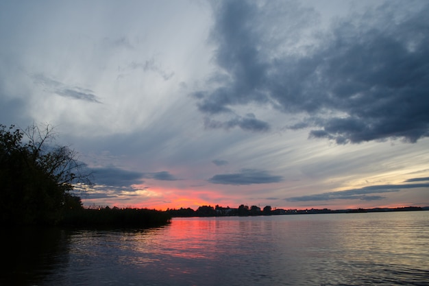 Il cielo variopinto e l&#39;acqua variopinta in lago hanno riflesso nella sera