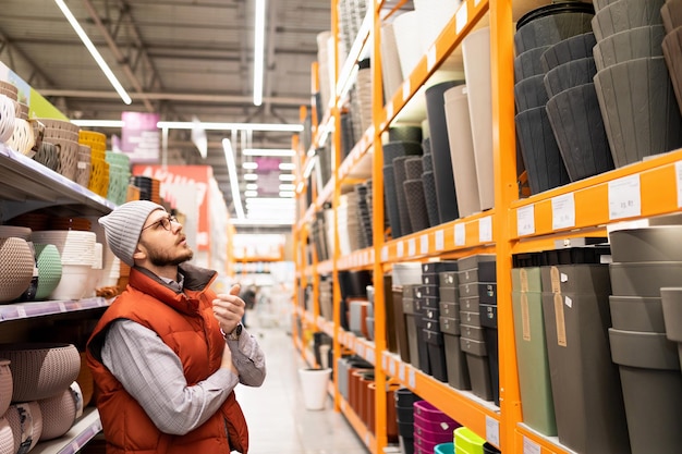 Il cliente del negozio di ferramenta sceglie il vaso per piante