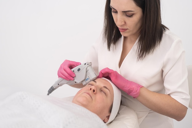 Il cliente femminile di mezza età riceve attrezzature professionali per il trattamento di lifting del viso con ultrasuoni laser